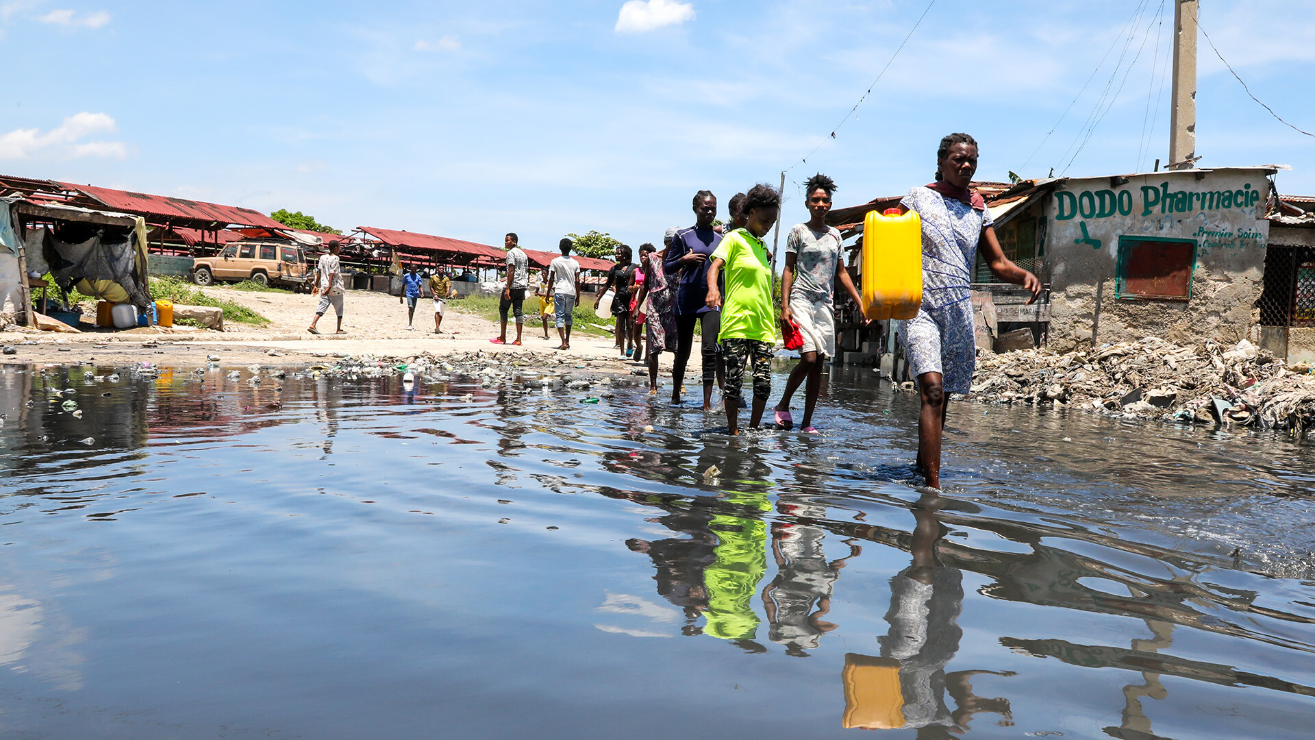 In Haiti gehen Menschen entlang von Gewässer.