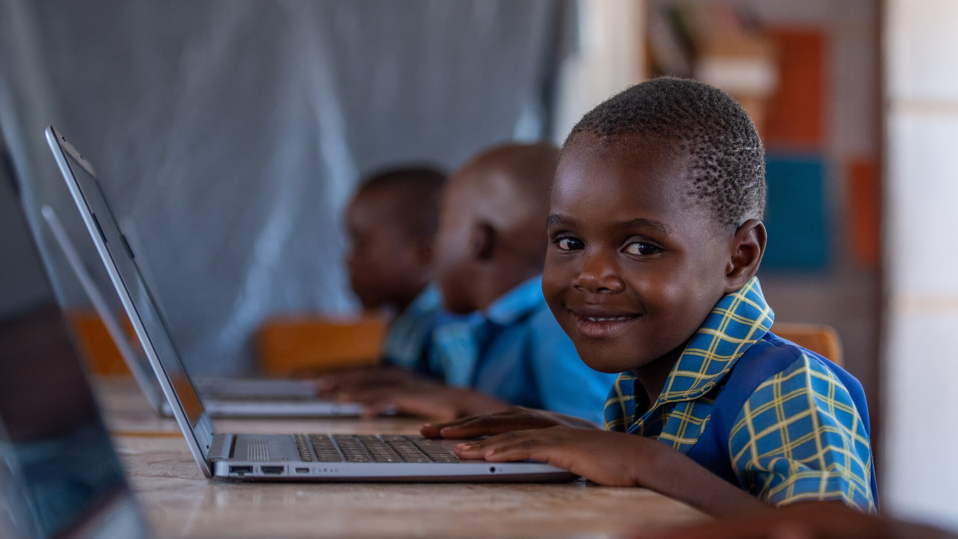 Ein Junge sitzt vor einem Laptop.