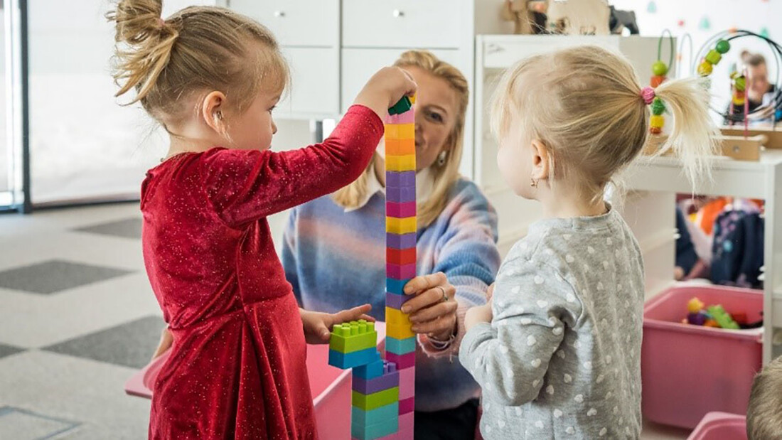 Zwei Mädchen bauen einen Tum aus Legosteinen.